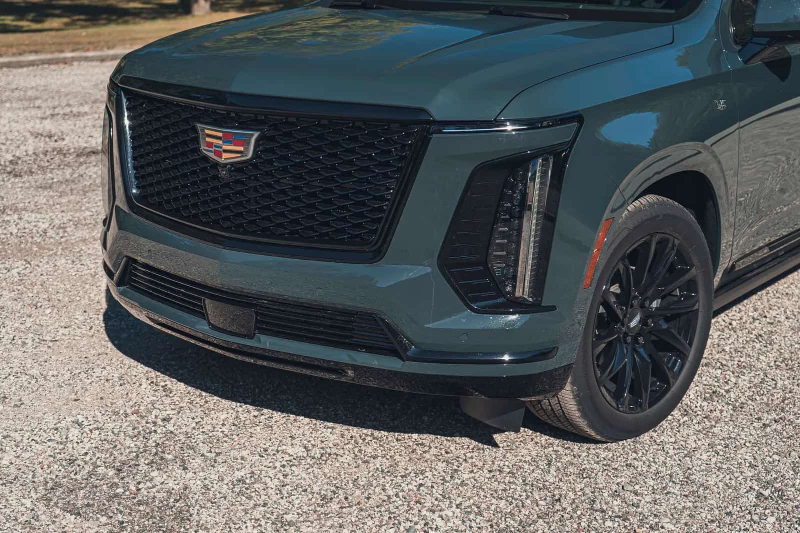 Grade, faróis e roda dianteira do Cadillac Escalade, vista próxima de três quartos dianteira