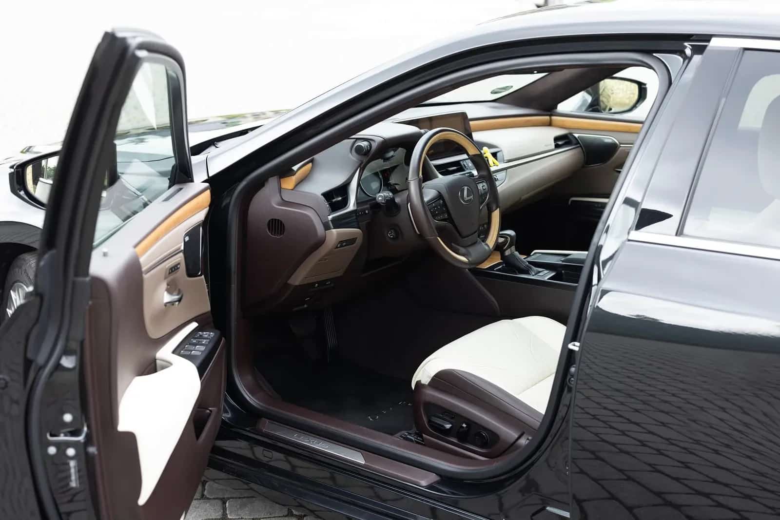 کھلے ڈرائیور دروازے سے Lexus ES کی اگلی نشستیں، کریم چمڑے میں