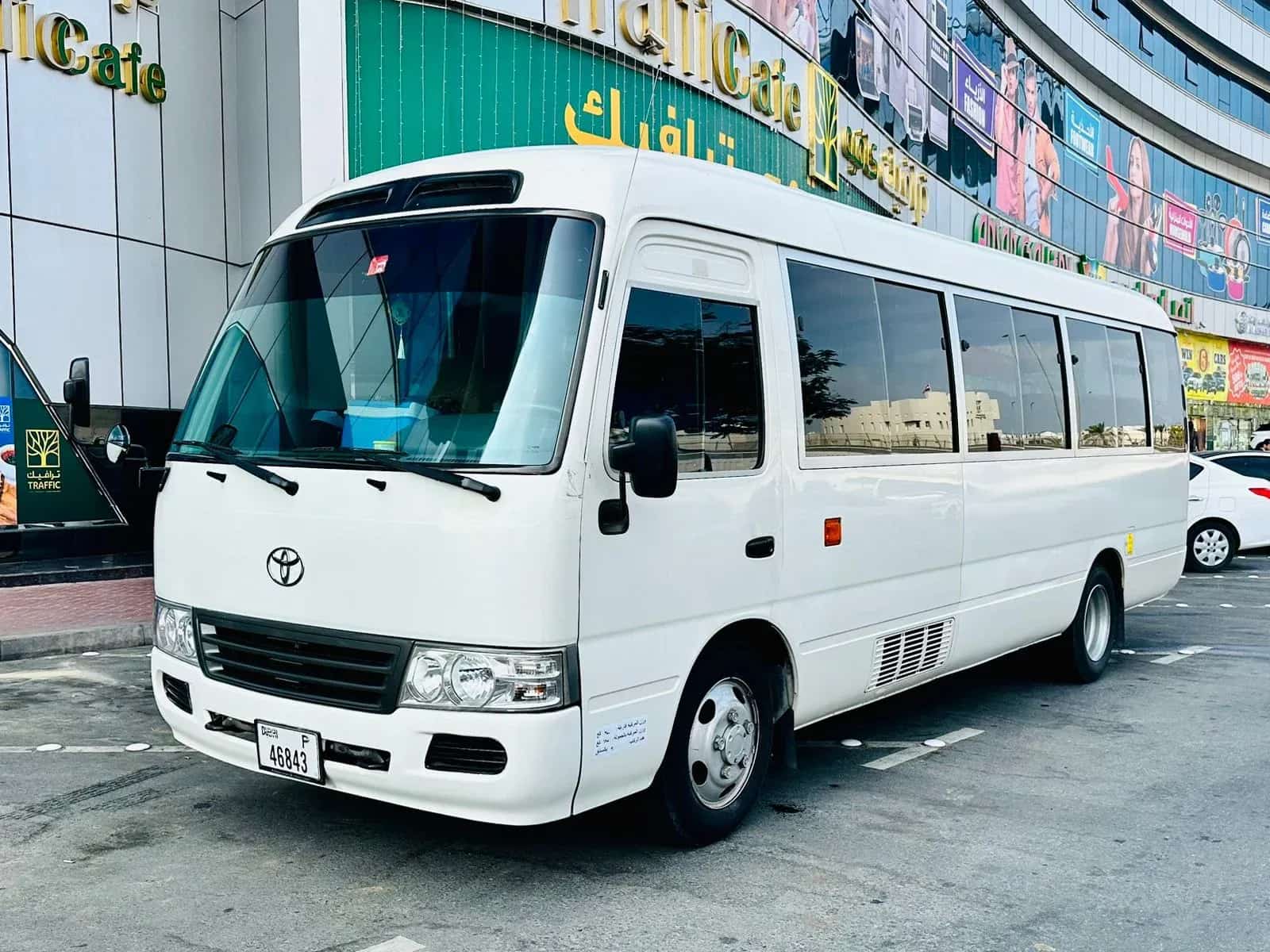 Micro-ônibus Toyota Coaster branco, vista de três quartos dianteira